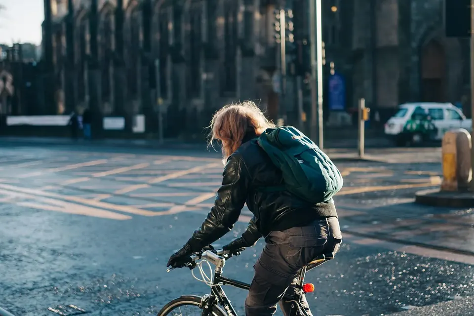 A cyclist riding along a cobbled street lined with stone buildings in Edinburgh