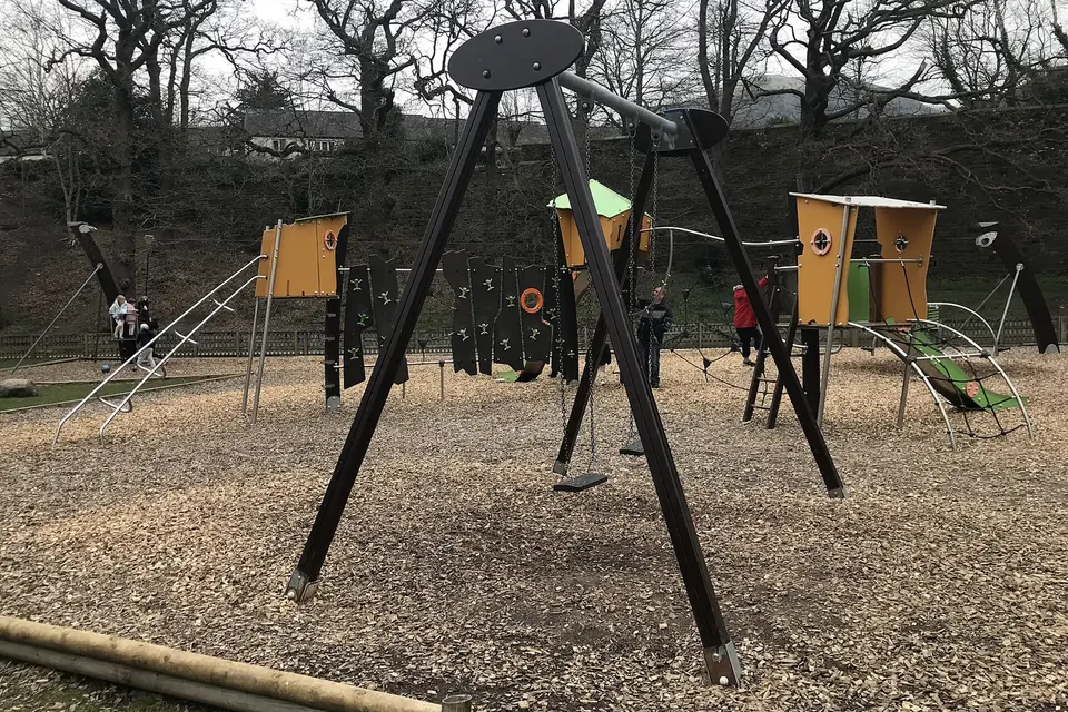 A swing and wooden play structures in an empty park playground