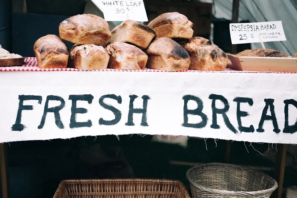 Bread rolls on a bakery counter above a hand-painted sign reading Fresh bread