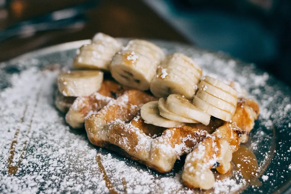 Waffles topped with banana slices and a dusting of icing sugar