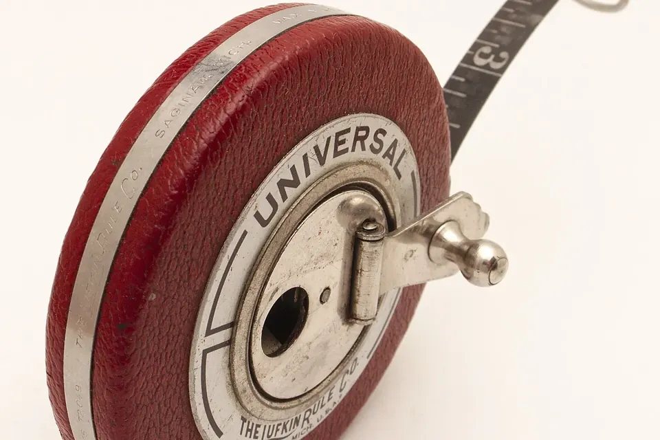 A round leather-cased surveyor's tape measure with a folding brass handle